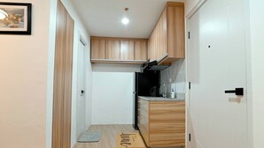 A compact kitchen with wooden cabinets, a black refrigerator, and a countertop with a coffee maker.