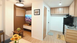 A compact living space with a kitchenette, a dining area with a table and chairs, a TV, and a small decorative plant.