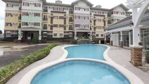 A multi-story residential building with a swimming pool in front.
