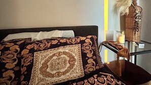 A bed with ornate pillows, a bedside table with a vase of dried plants, and a lamp. - Superb 3-bedroom house with AC in Broadbeach Waters (Broadbeach Waters)