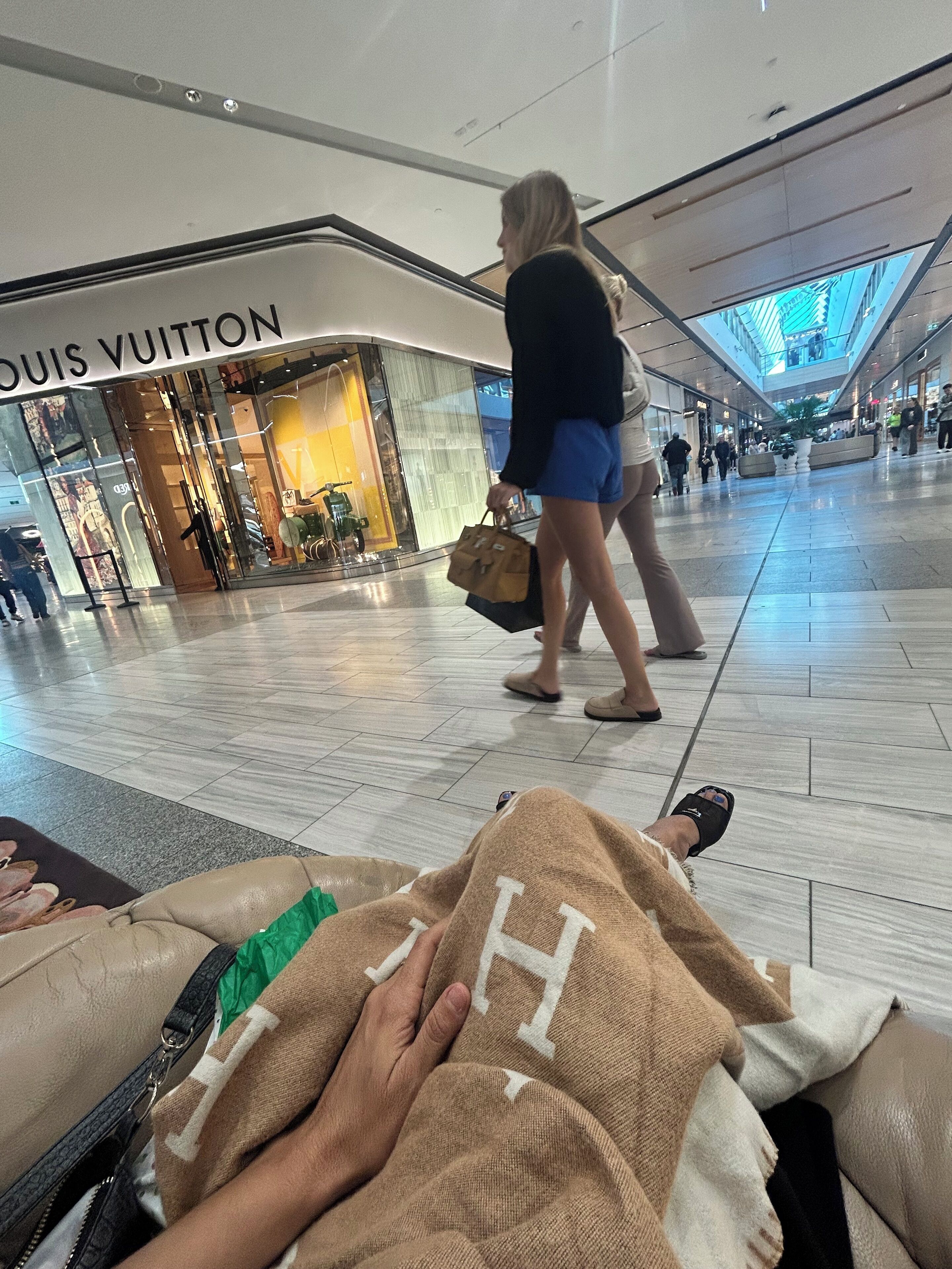 A spacious airport terminal with a Louis Vuitton store.