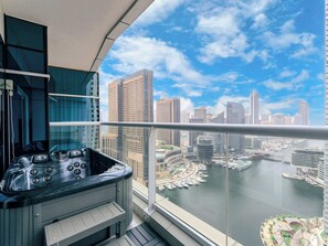 Un balcon avec un jacuzzi donnant sur un port de plaisance et sur le panorama de la ville.