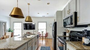 A modern kitchen with granite countertops, stainless steel appliances, and pendant lighting.