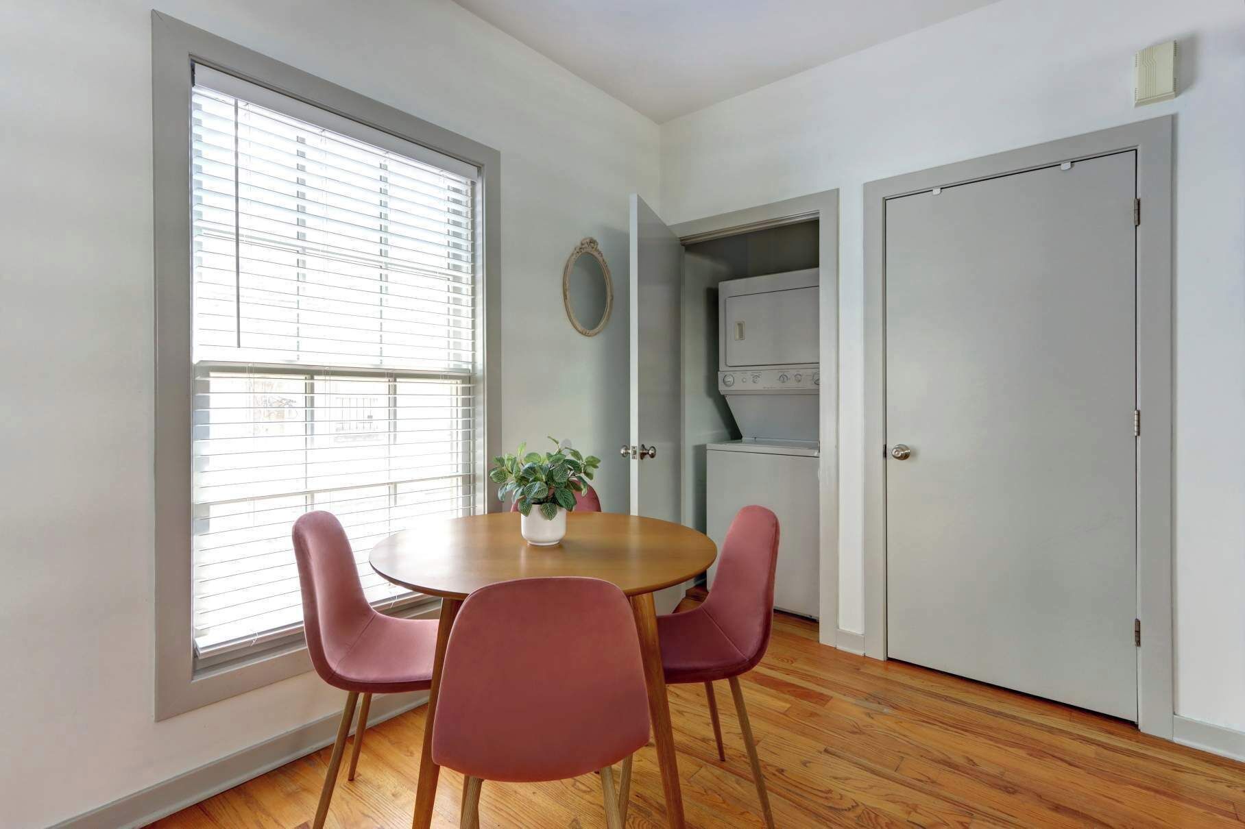 A dining area with a round table, four chairs, a potted plant, and a built-in oven.