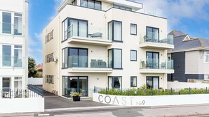 A modern multi-story residential building with balconies, large windows, and a white facade. - Rise and Shine - With a Balcony On the Seafront (Christchurch)