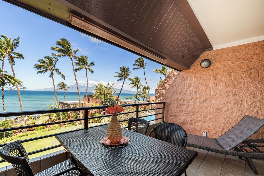 A balcony with a table, chairs, and a vase.
