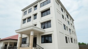 Un edificio de varios pisos con fachada blanca, numerosas ventanas y techo rojo.