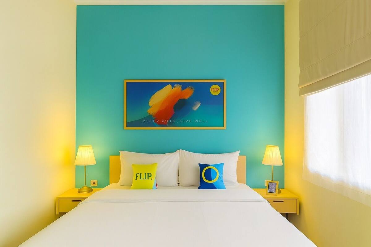 A bed with white bedding, two bedside lamps, and two pillows with text.
