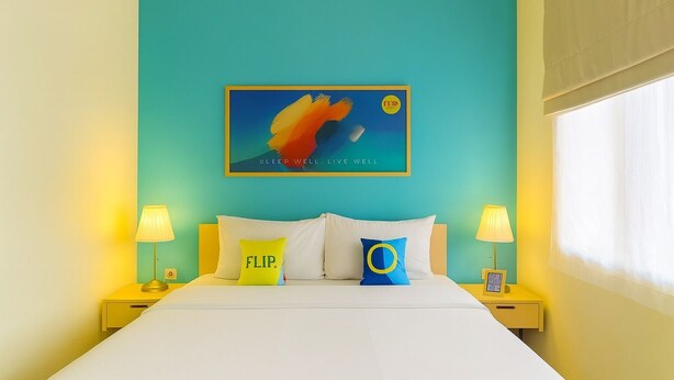 Una cama con ropa blanca, dos lámparas de noche y dos almohadas con texto.