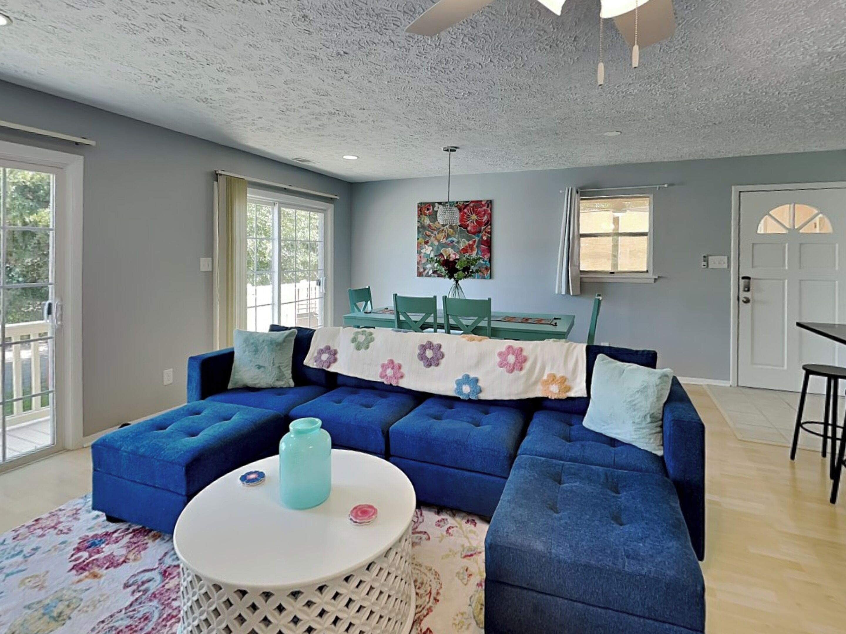 A living room with a sectional sofa, a round coffee table, and a dining area with a table and chairs.
