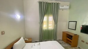 Una camera d'albergo con un letto, un comodino, una televisione e una finestra con tende.
