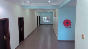 Un corridoio con pavimento lucido, una porta a sinistra e un oggetto rosso circolare sulla parete destra.