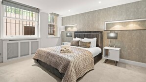 Une chambre moderne avec un grand lit, des tables de chevet et une fenêtre équipée de stores.