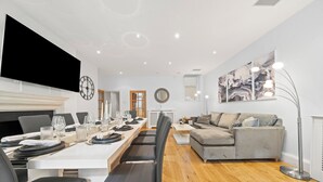 Un salon moderne avec un coin repas, comprenant un grand téléviseur à écran plat, une cheminée, un canapé et une table basse.