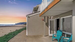 A beachfront property with a covered patio, outdoor seating, and a view of the ocean. - Oceanfront Ground Floor Studio  - Pool & Hot Tub! (Lincoln City)