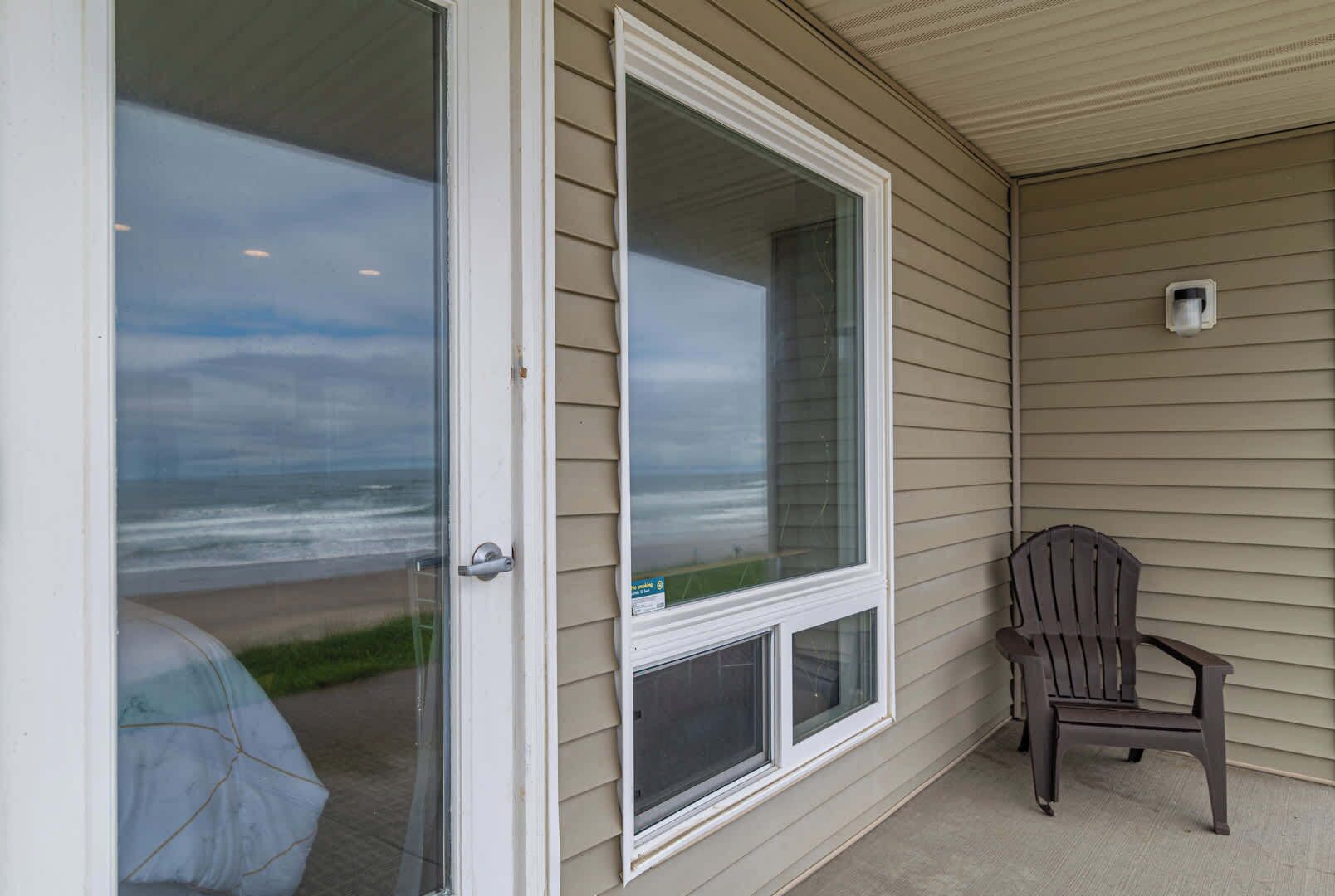 A covered porch with a sliding glass door leading to a beach view.