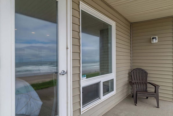A covered porch with a sliding glass door leading to a beach view. - Ground Level Oceanfront Studio, Beach Access, Pool (Lincoln City)