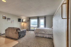 Een hotelkamer met een bed, een stoel, een televisie en uitzicht op de oceaan.