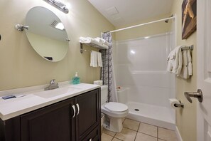 Een badkamer met een wastafel, spiegel, toilet en douche.