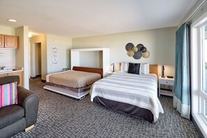 Une chambre d’hôtel avec deux lits, un canapé, un bureau et une grande fenêtre avec des rideaux.