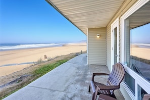 Ein Objekt direkt am Strand mit überdachter Veranda, einem Sessel und Blick aufs Meer.