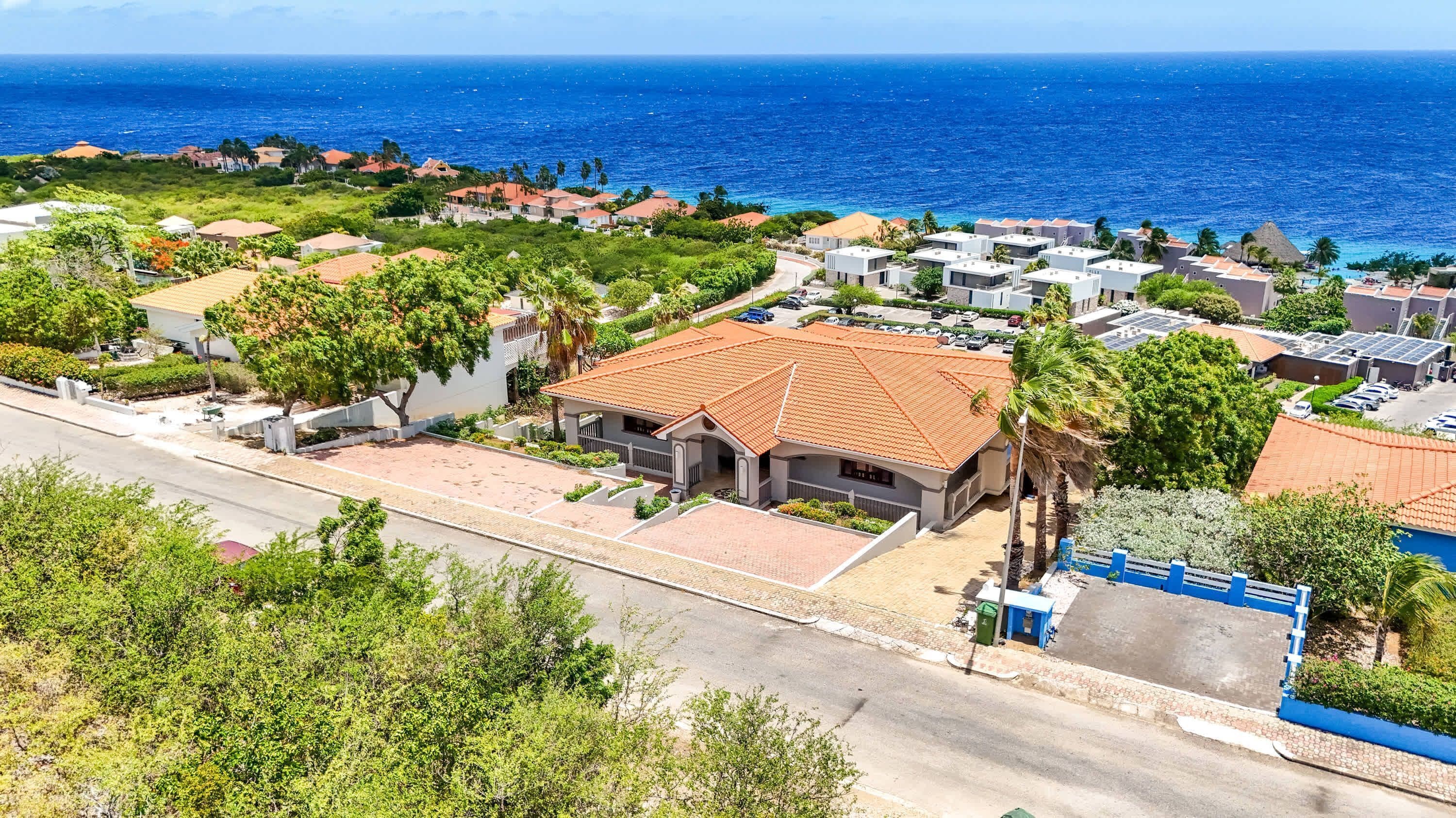 A coastal residential area with houses, a road, and a view of the ocean.