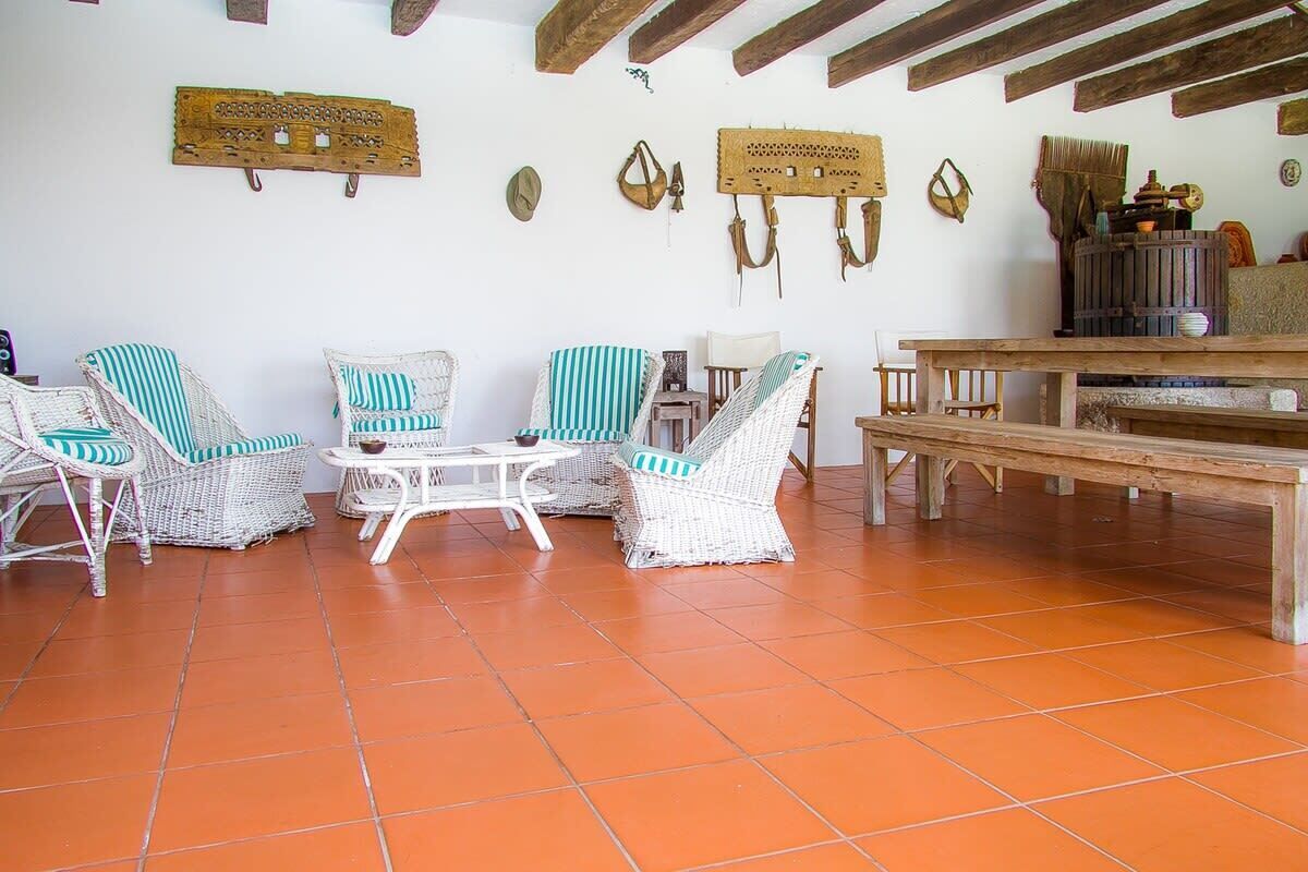 A room with wicker furniture, a wooden bench, and a tiled floor.