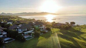 A coastal resort with multiple bungalow-style villas, a swimming pool, and a pier extending into the sea.