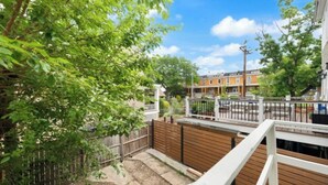 Un quartier résidentiel avec une clôture en bois, une rambarde blanche et un ciel dégagé.