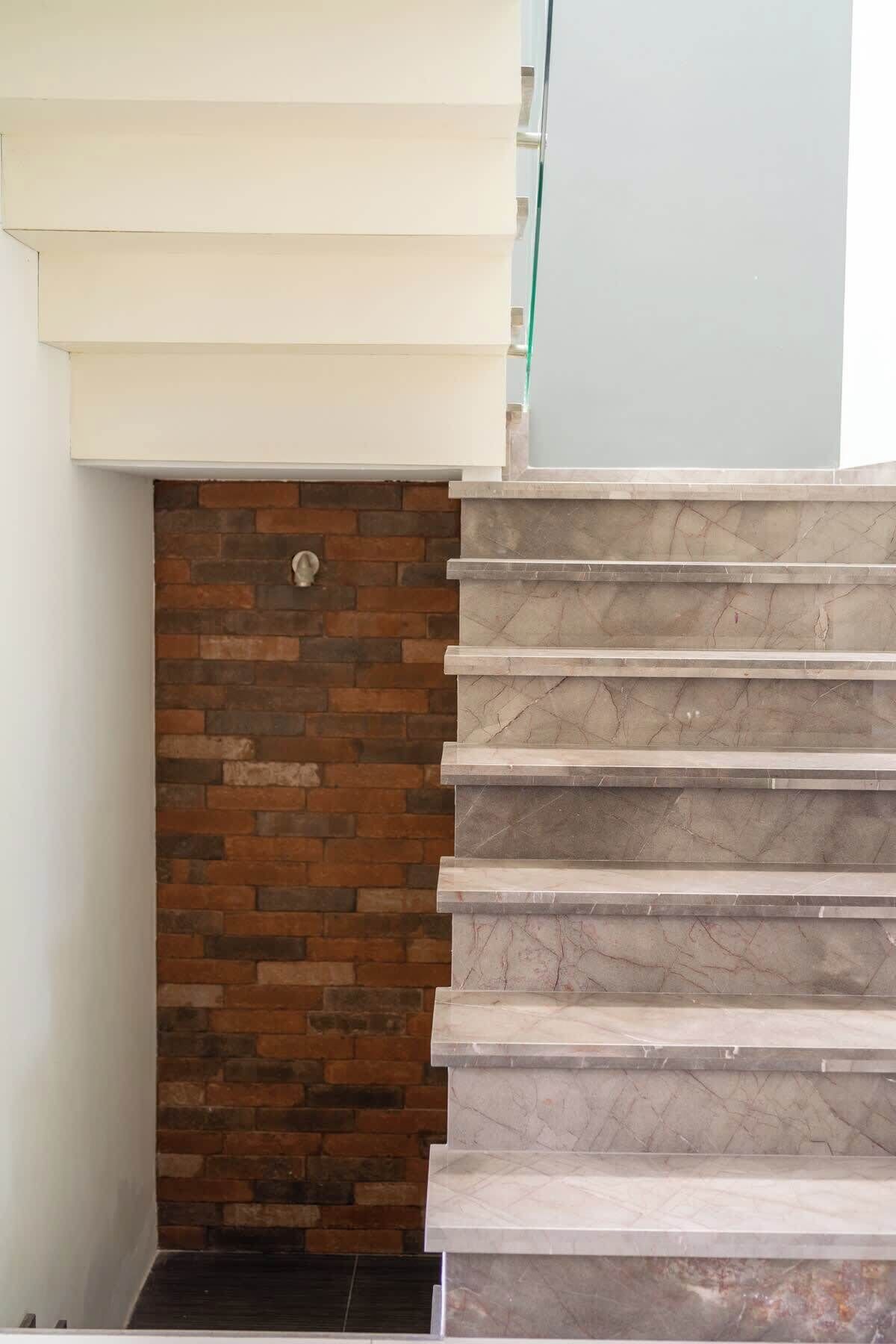 A staircase with a marble finish and a brick wall at the base.