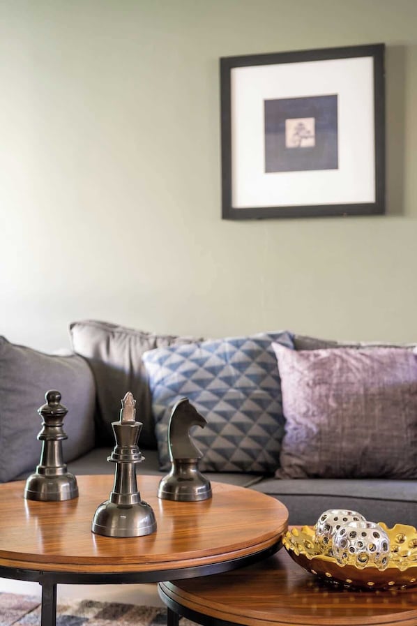 A round wooden coffee table with chess pieces and a decorative bowl.