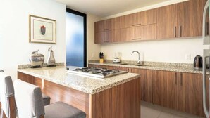 A modern kitchen with wooden cabinets, a granite countertop, a gas stove, and a built-in island with bar stools. - Family Residencia Galicia (La Tijera)