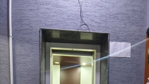 An elevator with a decorative floor panel, a control panel, and a wall-mounted light. - Skyry Residency (Chennai)