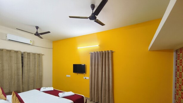 A hotel room with two beds, a ceiling fan, an air conditioner, a flat-screen TV, and curtains. - Skyry Residency (Chennai)