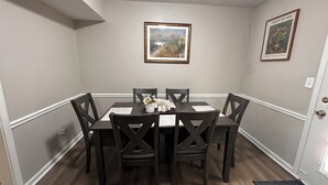 A dining area with a table and chairs, framed artwork on the wall, and a door with a lock. - Cozy house in Lawrenceville (Lawrenceville)