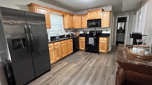 A modern kitchen with wooden cabinets, a stainless steel refrigerator, a microwave, and a stove. - Cozy house in Lawrenceville (Lawrenceville)