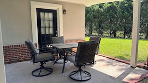 An outdoor patio with a table and four chairs, a door with a window, and a view of a green lawn. - Cozy house in Lawrenceville (Lawrenceville)