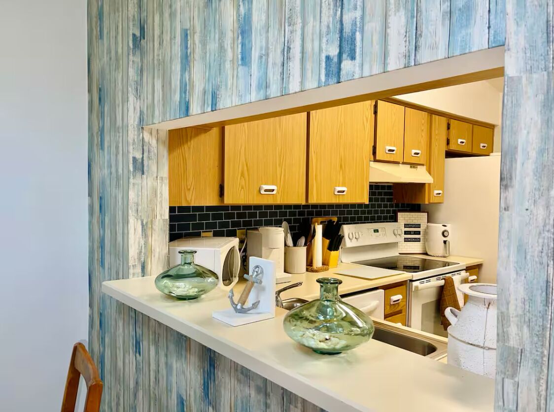 A modern kitchen with wooden cabinets, a white countertop, and a backsplash.