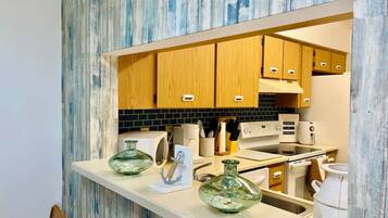 A modern kitchen with wooden cabinets, a white countertop, and a backsplash.