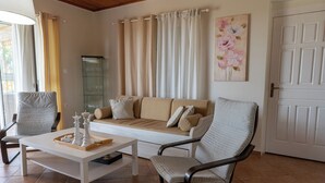 Un salon comprenant un canapé, deux fauteuils, une table basse et une vitrine.