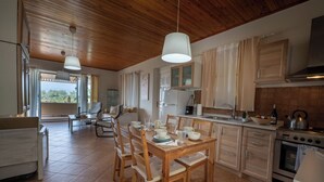 Une cuisine spacieuse avec des meubles en bois, une table à manger pour quatre personnes et une grande fenêtre qui laisse entrer la lumière naturelle.