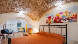 Une chambre à coucher avec un lit, une chaise, un bureau et un tableau accroché au mur.