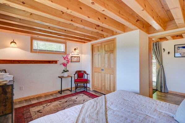 Une chambre à coucher avec un plafond en bois, un lit, une chaise, une fenêtre et une porte.