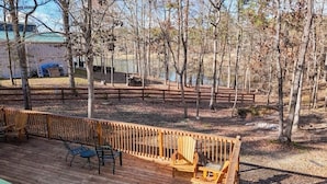 Una terraza con mobiliario exterior, una valla de madera y vistas a zona boscosa.