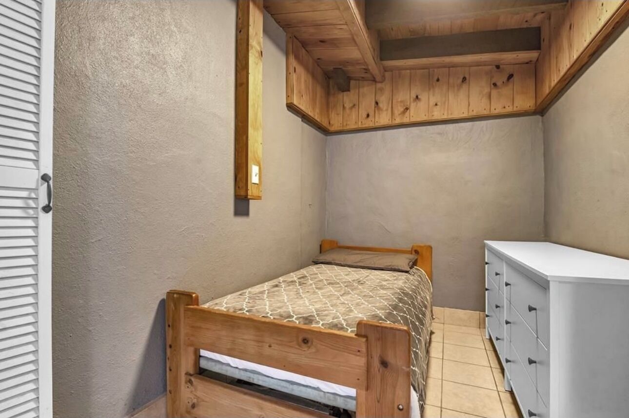 A small bedroom with a wooden bed, a white dresser, and a slanted ceiling.