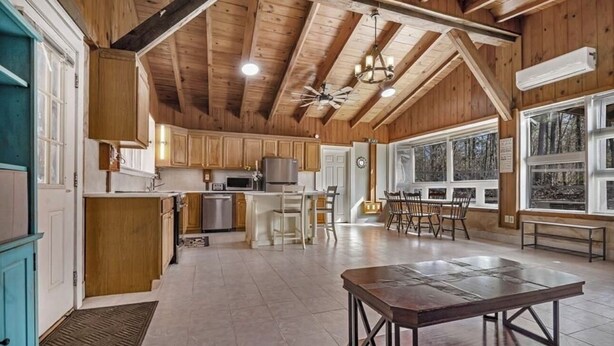 Una cocina amplia con armarios de madera, un comedor con una mesa grande y vistas al bosque a través de ventanas panorámicas.
