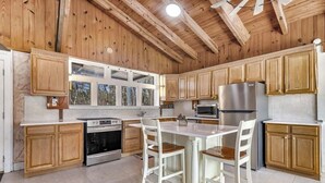 Una cocina con armarios de madera, encimera blanca y electrodomésticos de acero inoxidable.