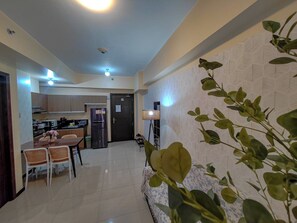 A modern kitchen with cabinets, a refrigerator, and a dining area with chairs and a table.