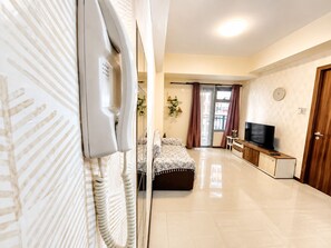 A hotel room with a bed, a television, a desk, and a door.