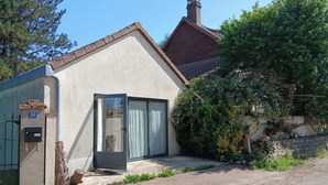 A small building with a door and a mailbox, surrounded by greenery and a gravel driveway. - Studio with terrace and garden 15 minutes from Guédelon (Treigny-Perreuse-Sainte-Colombe)